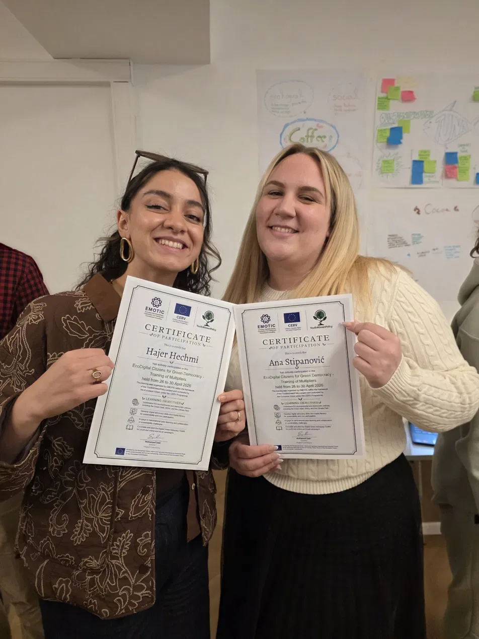 Two smiling participants holding up their certificates of participation after a five-day training of multipliers
