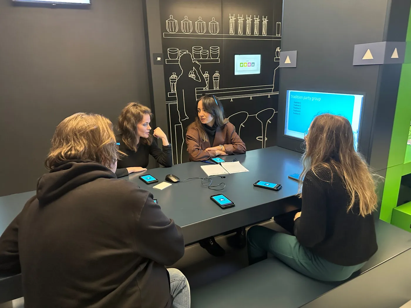 Four participants around a table with smartphones during an interactive group exercise