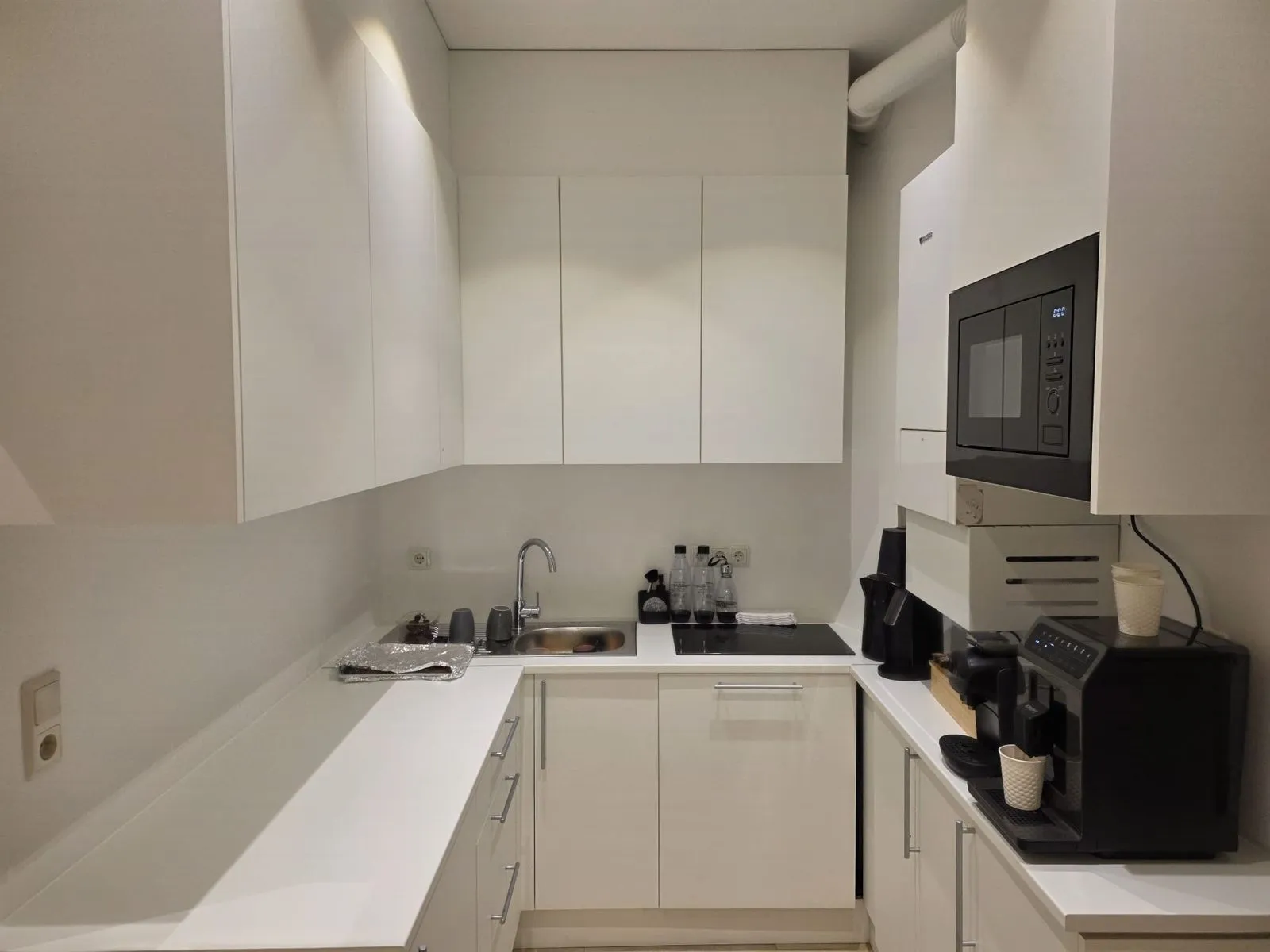 The kitchen with an espresso machine, kettle, microwave and hob