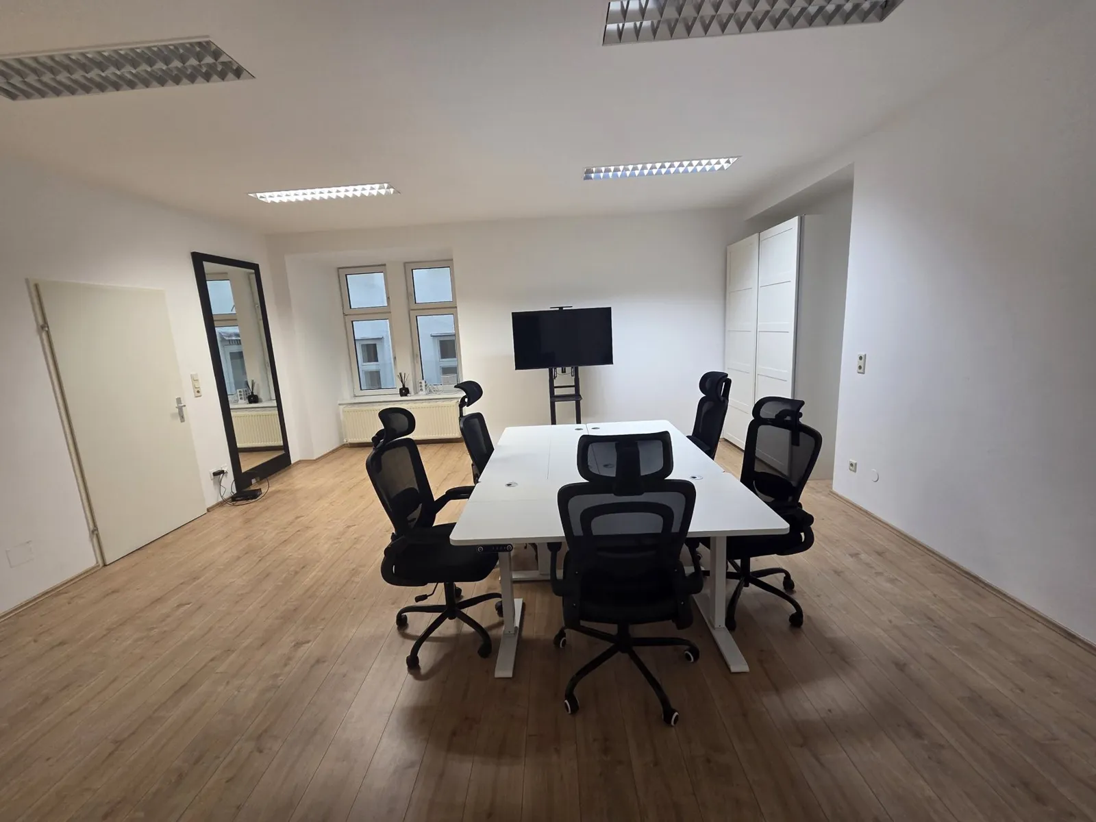 The workspace with white desks, ergonomic chairs and a screen