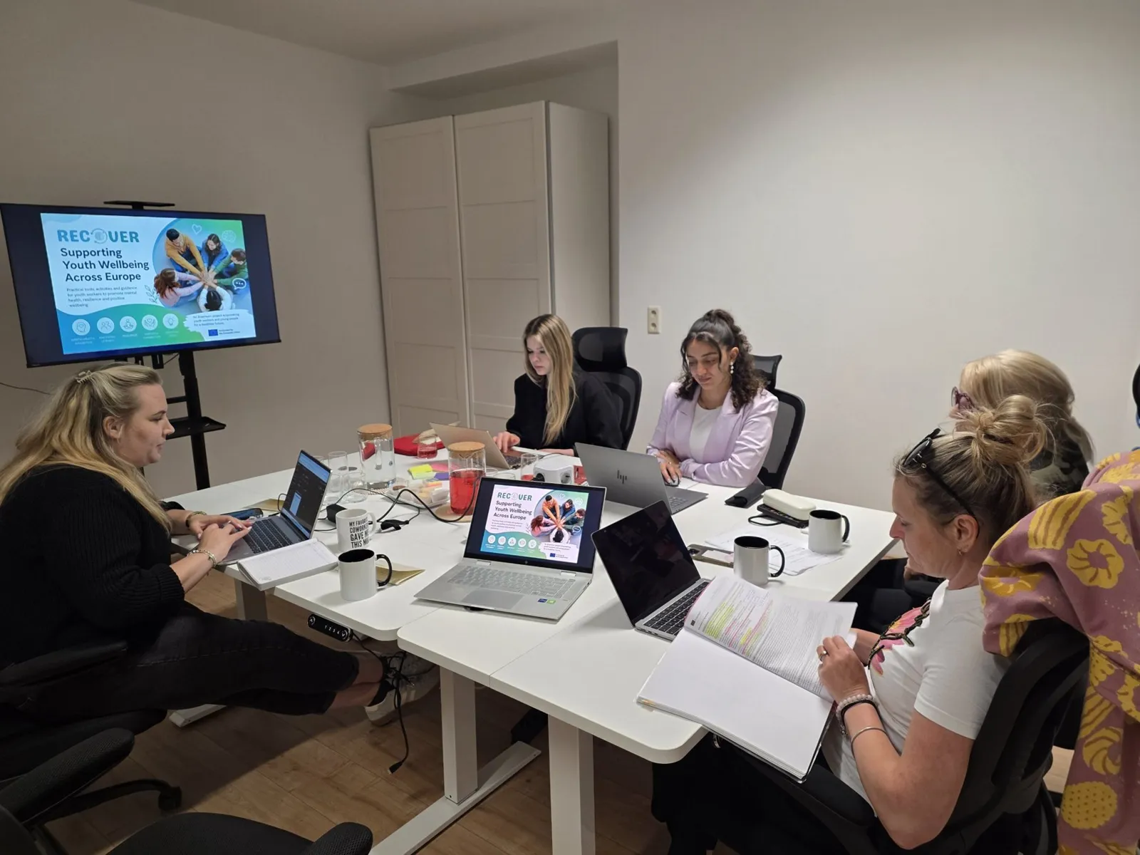 Team members working on laptops around a table during a project meeting
