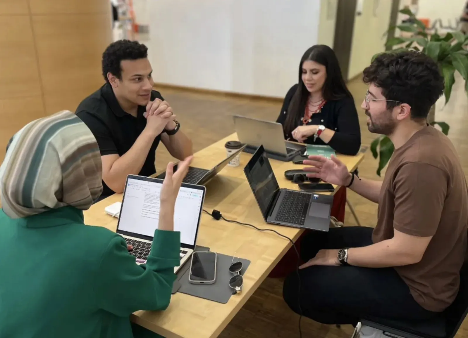 Four team members discussing their work around a table with laptops
